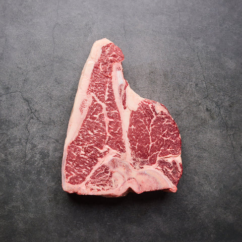 T-Bone Wagyu Steak BMS 8–9 Australia DIAMANTINA, ψημένο medium-rare, κομμένο σε φέτες γύρω από το κόκκαλο και σερβιρισμένο σε ξύλο κοπής.